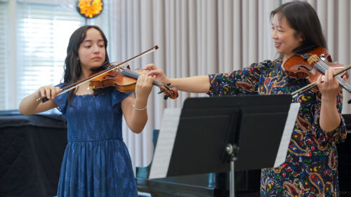 Maureen Yuen coaches a violin student in a blue dress during the NSA masterclass
