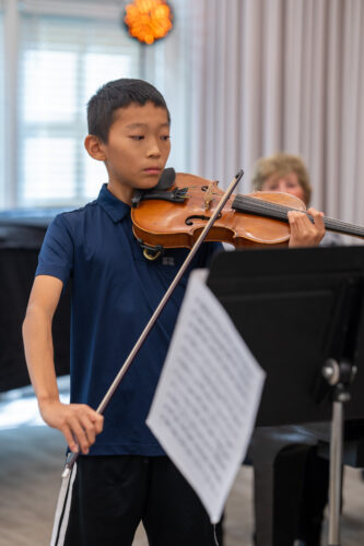 A young violinist reads music while performing
