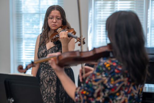 A student violinist listens as Maureen Yuen demonstrates a passage